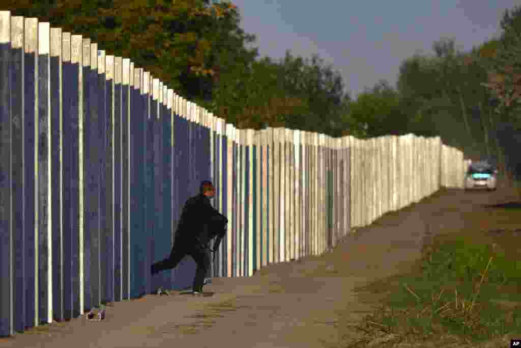 A migrant runs after he entered the territory of Hungary by crossing the temporary protection fence along the Hungarian-Serbian border as a Hungarian police car approaches at Roszke, 180 kms southeast of Budapest, Sept. 7, 2015.