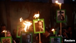 FILE - Journalists and demonstrators hold up pictures of slain journalist Javier Valdez Cardenas, at the Interior Ministry building in Mexico City, Mexico, May 16, 2017. 