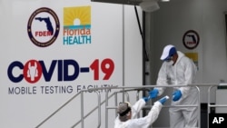 Health care workers work at a walk-up COVID-19 testing site during the coronavirus pandemic, July 17, 2020, in Miami Beach, Fla. 