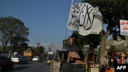 FILE - Taliban fighters travel on a vehicle mounted with the Taliban flag in the Karte Mamorin area of Kabul, Afghanistan, Aug. 22, 2021. 