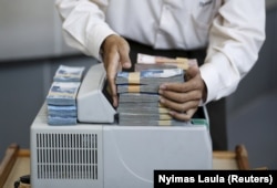 Seorang teller menumpuk Rupiah Indonesia di konter mata uang di dalam money changer di Jakarta, 4 Juni 2015. (Foto: Reuters/Nyimas Laula)