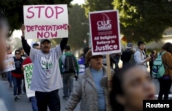 FILE - People hold signs while protesting against Immigration and Customs Enforcement raids in Los Angeles, California, Jan. 26, 2016.