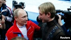 Russian President Vladimir Putin (L) greets Yevgeny Plushenko, a member of the gold medal-winning Russian figure skating team, during the 2014 Sochi Winter Olympics, Feb. 9, 2014. 