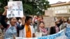 A supporter (L) holds up portraits of opposition lawmakers of the Cambodia National Rescue Party (CNRP) who were charged with leading an insurrection movement during a rally in front of Phnom Penh Municipality Court in Phnom Penh, Cambodia, July 17, 2014.