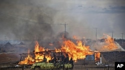 A machinegun-mounted truck manned by members of the Sudan Armed Forces (SAF) drive past burning businesses and homesteads in the center of Abyei, central Sudan in this handout photograph released by United Nations Mission in Sudan on May 28, 2011