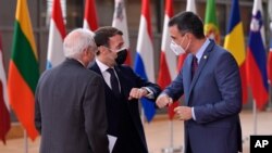 FILE - Spain's Prime Minister Pedro Sanchez, right, greets French President Emmanuel Macron, center, with an elbow bump during arrival for an EU summit at the European Council building in Brussels, Dec.10, 2020.