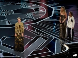 Frances McDormand accepts the award for best performance by an actress in a leading role for "Three Billboards Outside Ebbing, Missouri" as Jennifer Lawrence and Jodie Foster look on from right at the Oscars, March 4, 2018.