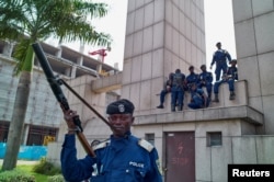 Congolese policemen sit on a monument at the Central Station, in Gombe, Kinshasa, Democratic Republic of Congo, Dec. 19, 2016.