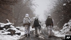 FILE - Ukrainian soldiers walks near the line of separation from Russia-backed rebels near Katerynivka, Donetsk region, Ukraine, Dec 7, 2021.