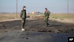 In this undated photo made avaialble March 14, 2015, by the Kurdistan Region Security Council, Kurdish soldiers survey what Kurds now say was the site of a chemical weapons bombing between Mosul, Iraq, and the Syrian border in northern Iraq.