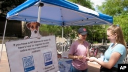 NextGen America campus organizer Simone Williams, left, talks with Grace Austin, a junior at the University of Wisconsin, about how to register to vote in Madison, Wisconsin, Aug. 30, 2018. 