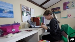 FILE - A student takes a class online at her home in San Francisco, March 19, 2020. Hundreds of students in Sioux Falls, South Dakota, did not take part in online learning when schools closed, one report shows.