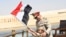 In this picture provided by the office of the Egyptian Presidency, President el-Sissi smiles at a boy dressed in a tiny military uniform as he waves the national flag from a monarchy-era yacht that sailed to the venue of a ceremony for extension of the Su
