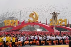 FILE - Attendees wave Chinese flags during a ceremony at Tiananmen Square to mark the 100th anniversary of the founding of the ruling Chinese Communist Party in Beijing.
