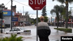A resident watches as floodwaters enter the main street of Lismore, Australia, March 31, 2017, after heavy rains associated with Cyclone Debbie swelled rivers to record heights across the region.