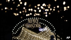 A woman wearing a face mask as a precaution against the coronavirus takes a photo near a Christmas decoration in Seoul, South Korea, Dec. 24, 2020.