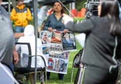 A woman holds images, some showing former Lebanese Prime Minister Rafik Hariri, outside the U.N.-backed Lebanon Special Tribunal in Leidschendam, Netherlands, Aug. 18, 2020.