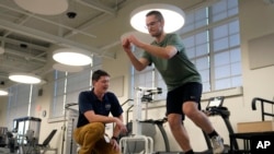 Physical therapist Tyler Detmer, left, works with patient Jacob Bullard at WashU, Monday, Dec. 16, 2024, in St. Louis. (AP Photo/Jeff Roberson)