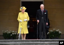 Britain's Queen Elizabeth and Prince Philip observe a minute's silence, at the start of a garden party at Buckingham Palace in London, May 23, 2017.