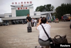 A Chinese tourist poses for pictures at the border between between China and North Korea, in Hunchun, Jilin province August 29, 2011.