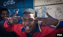 A young man postures, making a handgun gesture, in Cape Town's Hanover Park. Gang shootings are all too familiar in the township. (H. FitzPatrick/VOA)