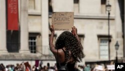 A woman holds up a banner as people gather in Trafalgar Square in central London, May 31, 2020, to protest against the recent killing of George Floyd by police officers in Minneapolis that has led to protests across the U.S.
