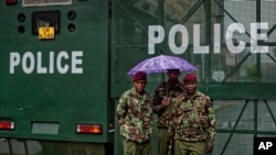 FILE - Kenyan police stand in the rain by a barrier blocking off vehicle and pedestrian access, amid tight security outside the Supreme Court in Nairobi, Kenya, Nov. 14, 2017.