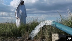 A farmer stands near a water pump on his farm in Youssifiyah, Iraq, April 23, 2019. In the farming region, just south of the capital, wells that were dug 24 meters deep to reach a sinking water table are producing water at just 6 meters depth.