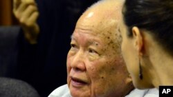 In this photo released by the Extraordinary Chambers in the Courts of Cambodia, Khieu Samphan, left, former Khmer Rouge head of state, sits in the court room during a hearing at the U.N.-backed war crimes tribunal, in Phnom Penh, Cambodia, Oct. 17, 2014.