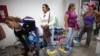 FILE - Shoppers wait in line to check out at a supermarket in the Propatria neighborhood of Caracas, Venezuela.