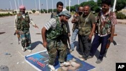 FILE - In this Saturday, Sept. 22, 2012 file photo, a Free Syrian Army fighter from the Al-Faruk brigade, center, steps on a portrait of Syrian President Bashar Assad.