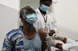 An Ivory Coast national gendarmerie officer receives the AstraZeneca COVID-19 vaccine at the palais des sports in Abidjan, March 1, 2021.