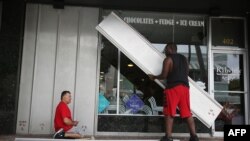Jason Brock, left, and Kevin Hunter put up hurricane shutters in front of a business as Hurricane Matthew approaches the area on Oct. 6, 2016 in Delray Beach, Florida.