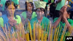FILE - Cambodian villagers with their faces painted to resemble the forest people from the film 'Avatar' pray during a rally against the destruction of the Prey Lang forest in front of the Royal Palace in Phnom Penh, Aug. 18, 2011.