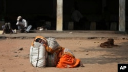 FILE - An Indian attendant of a patient suspected with swine flu virus rests on the ground in the premises of Gandhi Hospital in Hyderabad, India, Wednesday, Jan. 21, 2015. According to local reports, nine people died of the flu at the state-run hospital. 