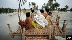 Pakistani villagers make their way through flood waters in Baseera, Pakistan, 24 Aug 2010