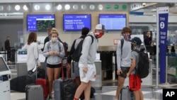 Travelers wearing maskes talk in a terminal at O'Hare International Airport, in Chicago, Illinois, Nov. 20, 2020. 