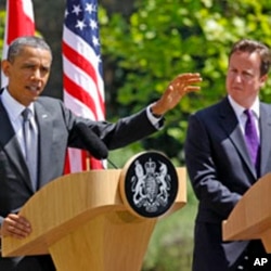 British Prime Minister David Cameron (R) watches U.S. President Barack Obama speak to reporters at Lancaster House in London May 25, 2011
