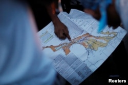 A migrant, part of a caravan of thousands traveling from Central America en route to the United States, points at a map while rest in Santiago Niltepec, Mexico, Oct. 29, 2018.