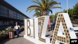 A tourist walks with her suitcase outside the airport in the Spanish island of Ibiza on July 30, 2020.