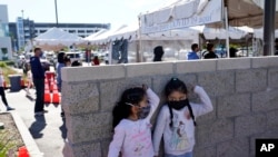 Two girls wait in line at a COVID-19 testing site on the Martin Luther King Jr. medical campus on Jan. 3, 2022, in Los Angeles.
