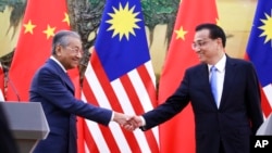 FILE - Malaysian Prime Minister Mahathir Mohamad, left, shakes hands with his Chinese counterpart Li Keqiang at the end of a press conference at the Great Hall of the People in Beijing, Aug. 20, 2018.
