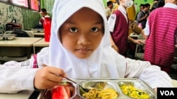 A girl begins her free meal of rice, chicken, tofu, stir-fried corn and watermelon. (Devianti Faridz/VOA)