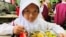 A girl begins her free meal of rice, chicken, tofu, stir-fried corn and watermelon. (Devianti Faridz/VOA)