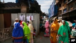 ফাইল-বোহরা সম্প্রদায়ের এক পাড়ায় পোশাক কেনাকাটায় ব্যস্ত কয়েকজনের পাশ দিয়ে হেঁটে যাচ্ছেন ভারতীয় দাউদি বোহরা নারীরা। মুম্বাই, ভারত। ২১ ফেব্রুয়ারি, ২০১৬। 