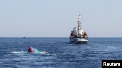 FILE - A Vietnamese sinking boat (L) which was rammed and then sunk by Chinese vessels near disputed Paracels Islands, is seen near a Marine Guard ship (R) at Ly Son island of Vietnam's central Quang Ngai province.
