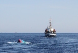 FILE - A Vietnamese sinking boat (L) which was rammed and then sunk by Chinese vessels near disputed Paracels Islands, is seen near a Marine Guard ship (R) at Ly Son island of Vietnam's central Quang Ngai province.