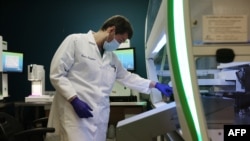 Lab technician Carter Tavaglione loads a Janus G3 automated workstation with coronavirus test samples at Advagenix, a molecular diagnostics laboratory, on Aug. 5, 2020 in Rockville, Maryland. 