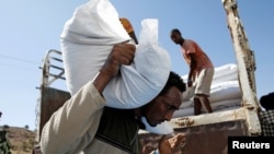 FILE - A man carries a sack of food aid from the WFP, at the Um Rakuba refugee camp in Sudan, where Tigray refugees stay, Dec. 3, 2020.