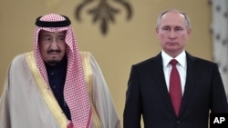 FILE - In this Oct. 5, 2017 file photo, Russian President Vladimir Putin, right, and Saudi Arabia's King Salman pose for a photo during a welcoming ceremony in Moscow.